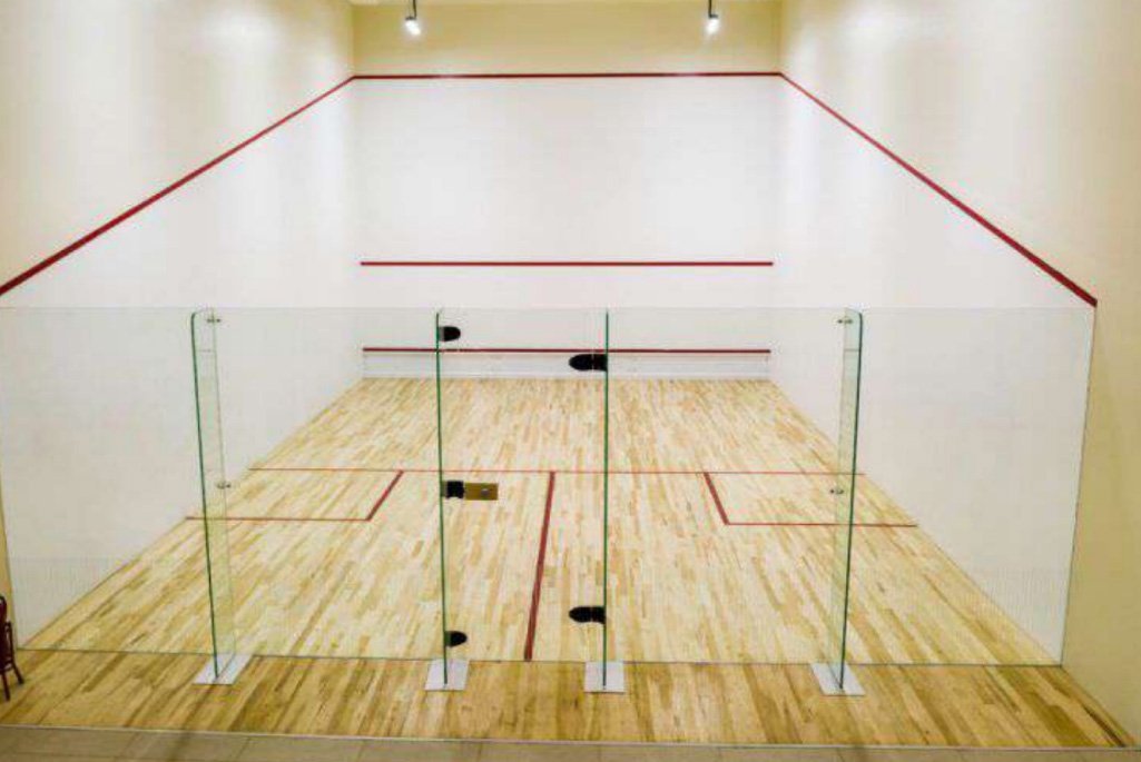 Indoor squash court with wooden flooring and glass back wall