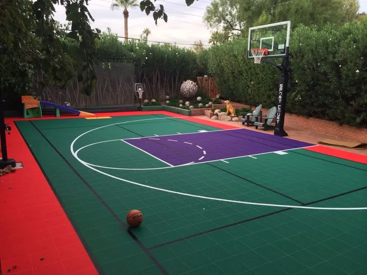 Colorful outdoor basketball court with green, red, and purple synthetic flooring in residential area