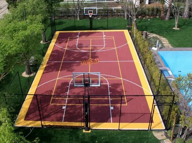 Custom-designed outdoor basketball court with red and yellow synthetic flooring near swimming pool