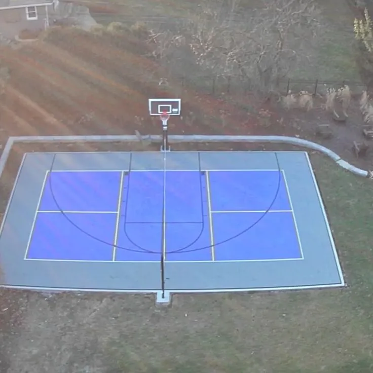 Outdoor multi-use sports court with blue synthetic flooring and basketball hoop