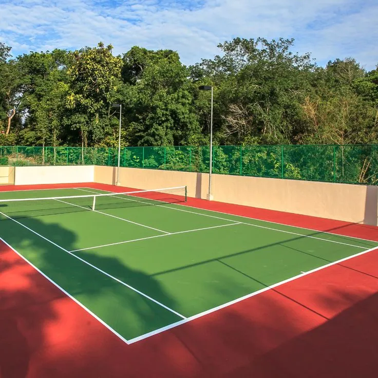 Outdoor synthetic tennis court with green and red acrylic surface and net
