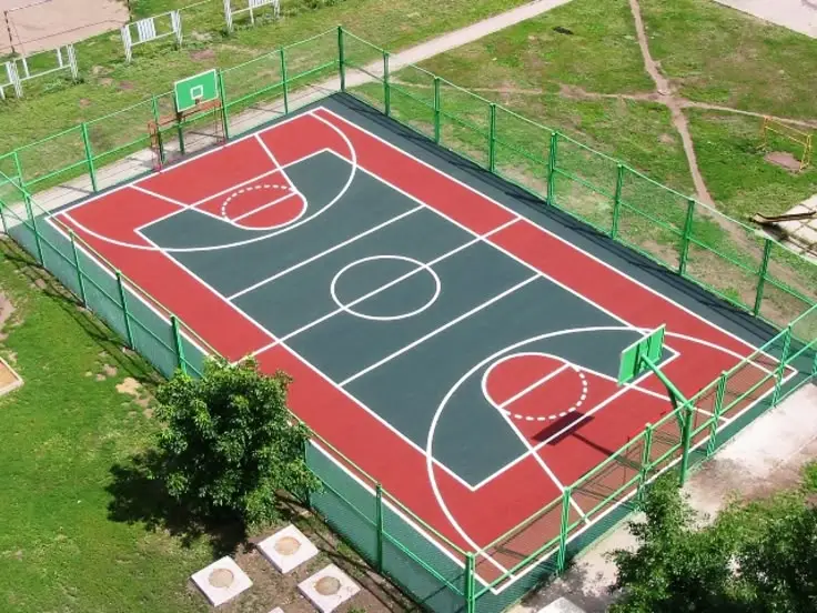Outdoor basketball court with synthetic acrylic flooring, fenced area and clear line markings