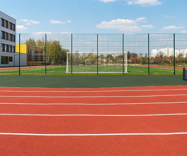 Outdoor EPDM jogging track with red rubber surface and lane markings near sports ground