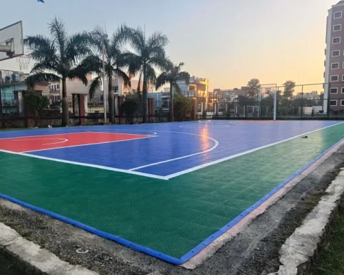 Synthetic outdoor basketball court with colorful flooring and sunset view