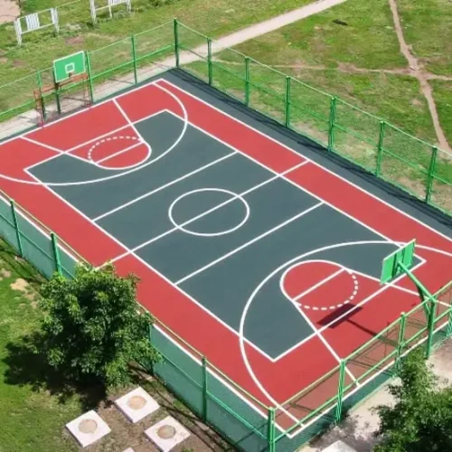 Outdoor basketball court with synthetic acrylic flooring, fenced area and clear line markings
