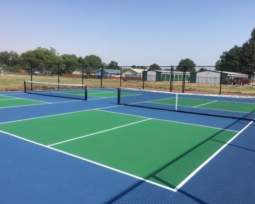 Outdoor pickleball court with net and blue-green acrylic surface