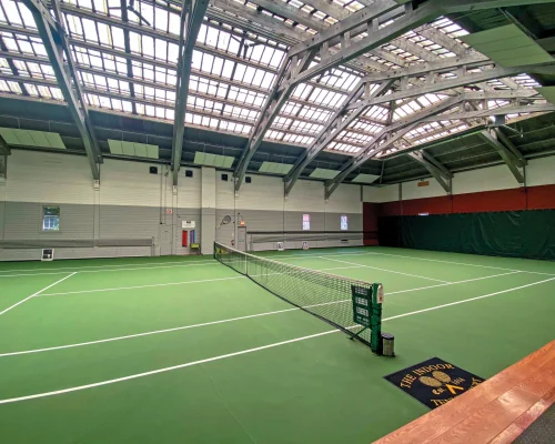 Indoor tennis court with professional sports flooring and net setup